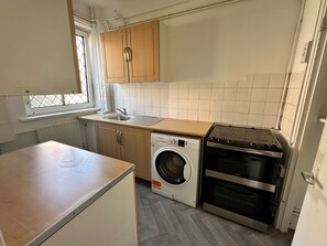 A compact kitchen with a washing machine, oven, and a window with a view. - Cozy Apartment in Central London by Tower Bridge (London)