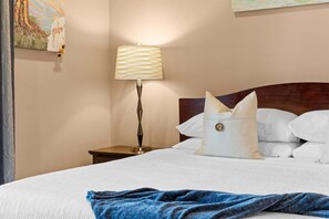 Ein Hotelzimmer mit Bett, Nachttisch, Lampe und einem Bild an der Wand.
