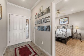A hallway with a white door, a red rug, and a wall with framed photographs. - Yakov's Pointe Pool Access (Hollister)