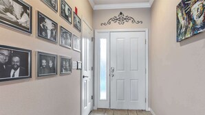 Ein Flur mit einer weißen Tür, einem roten Teppich und mehreren gerahmten Fotos an der Wand.