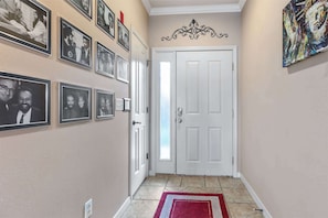 Ein Flur mit einer weißen Tür, einem roten Teppich und mehreren gerahmten Fotos an der Wand.
