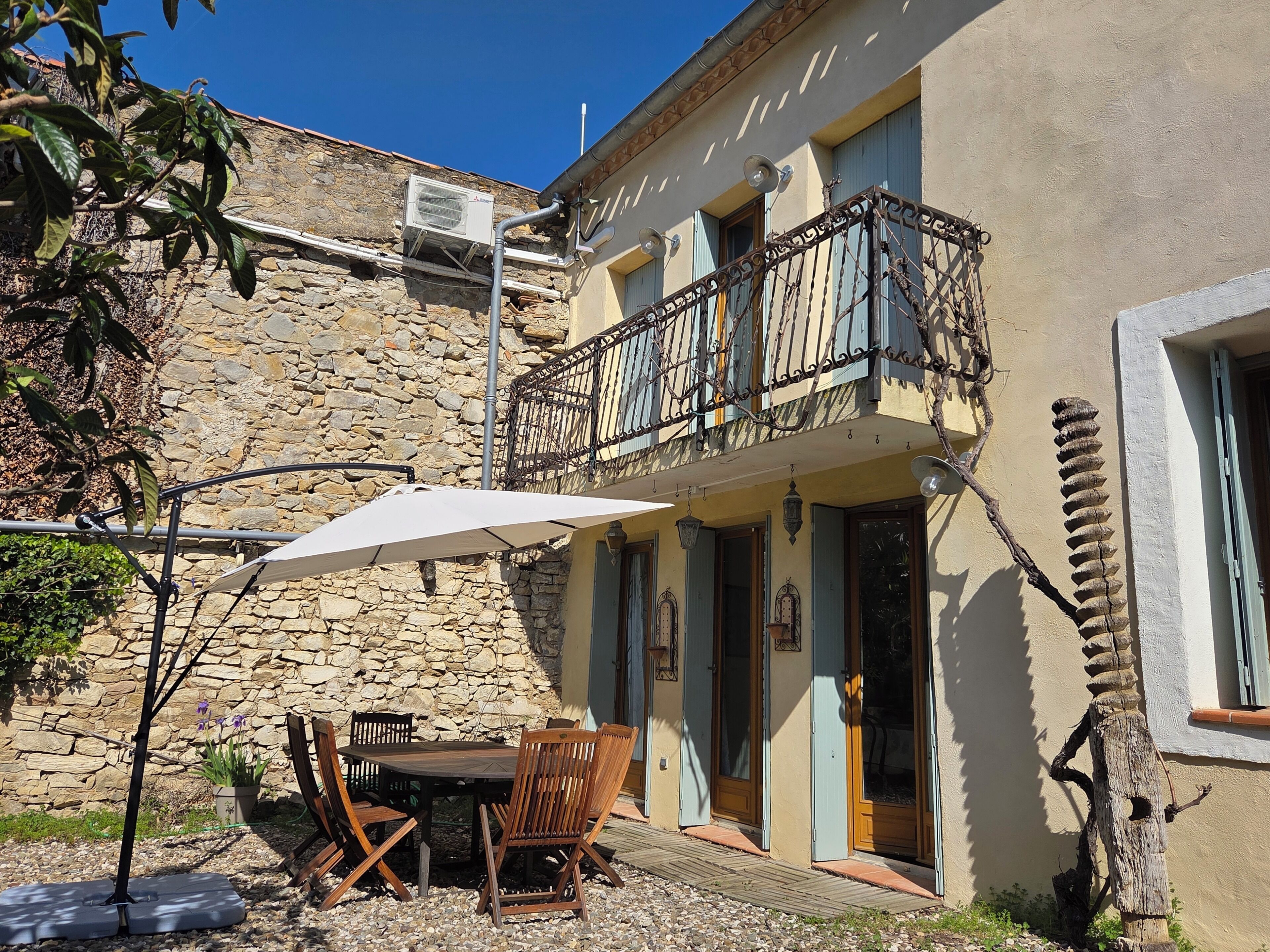 Un edificio in pietra con un balcone, posti a sedere all'aperto e un tavolo con sedie.