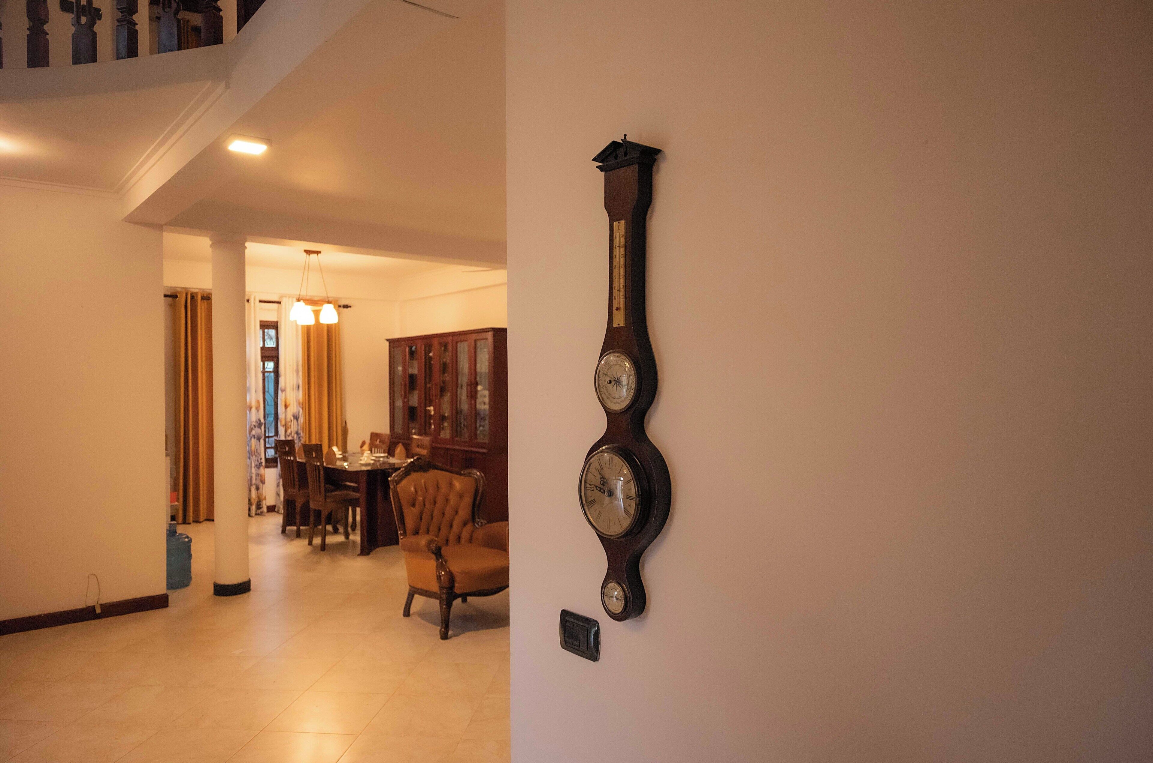 A hallway with a dining area, a clock on the wall, and a staircase.