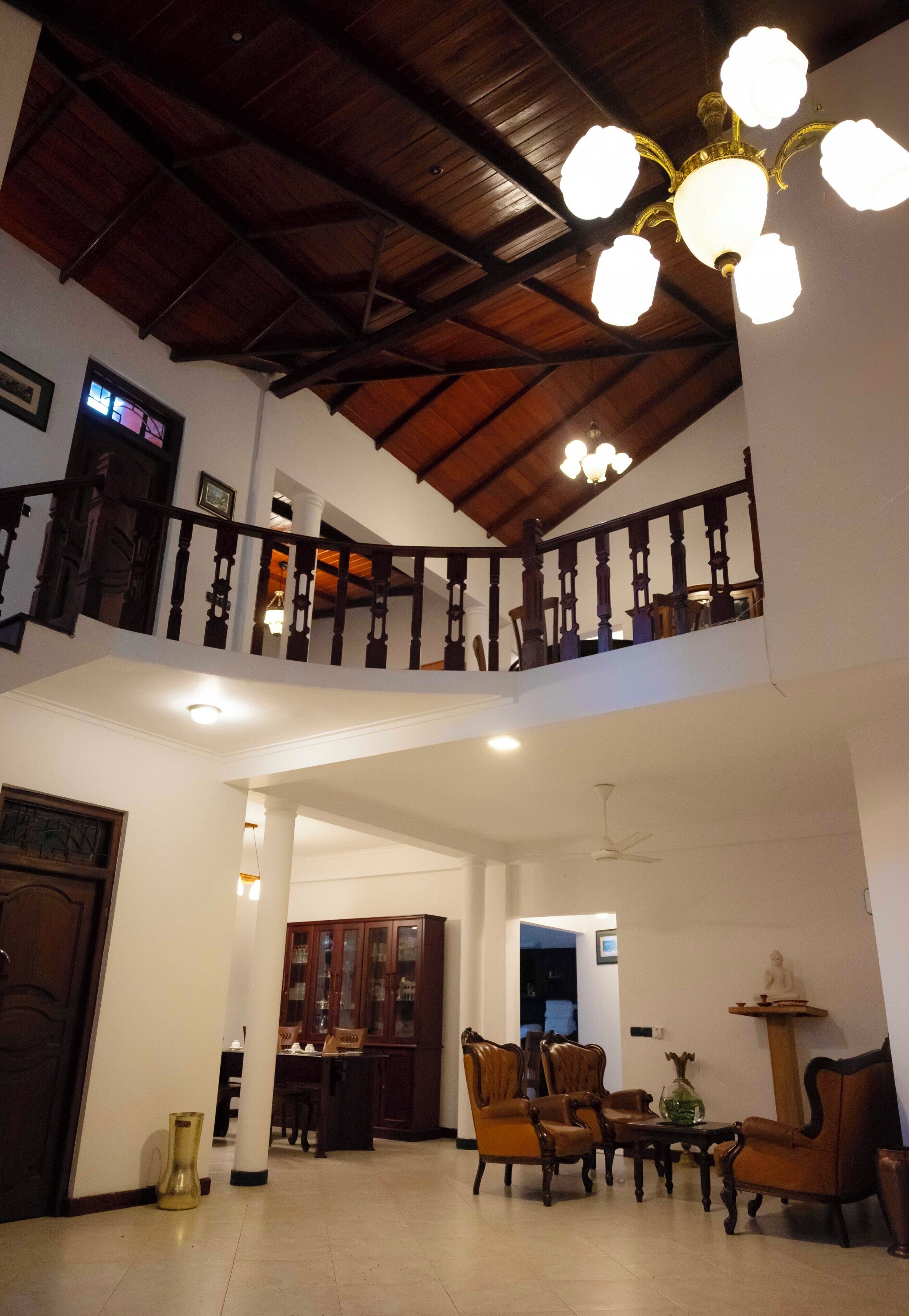A spacious interior with a high ceiling, a staircase, and a dining area with wooden furniture.