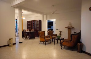 Uma sala de estar espaçosa com área de jantar, um ventilador de teto e uma estátua em uma prateleira.