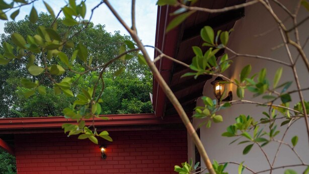 Ein rotes Backsteinhaus mit einer gefliesten Terrasse und einem Baum im Vordergrund.