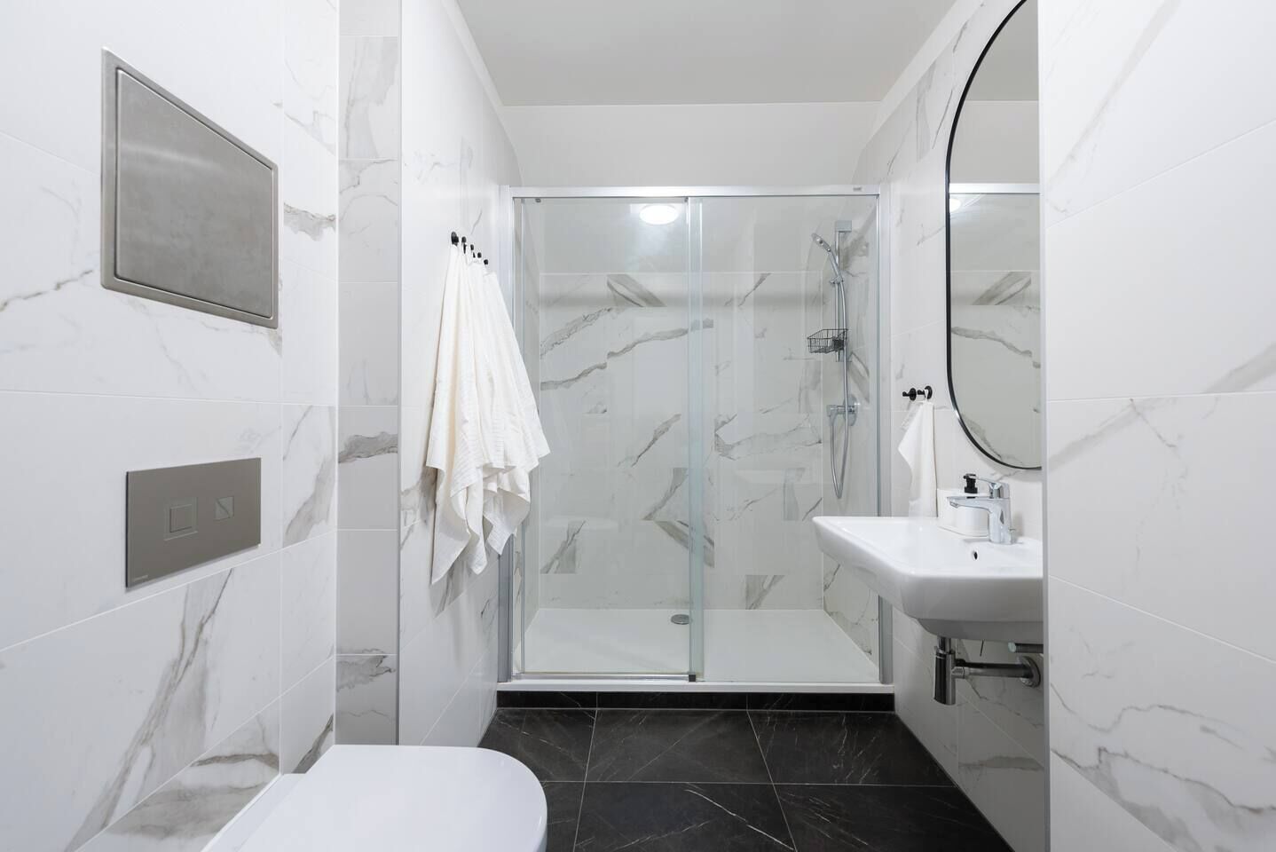 A modern bathroom with a glass-enclosed shower, a white sink, and a toilet.