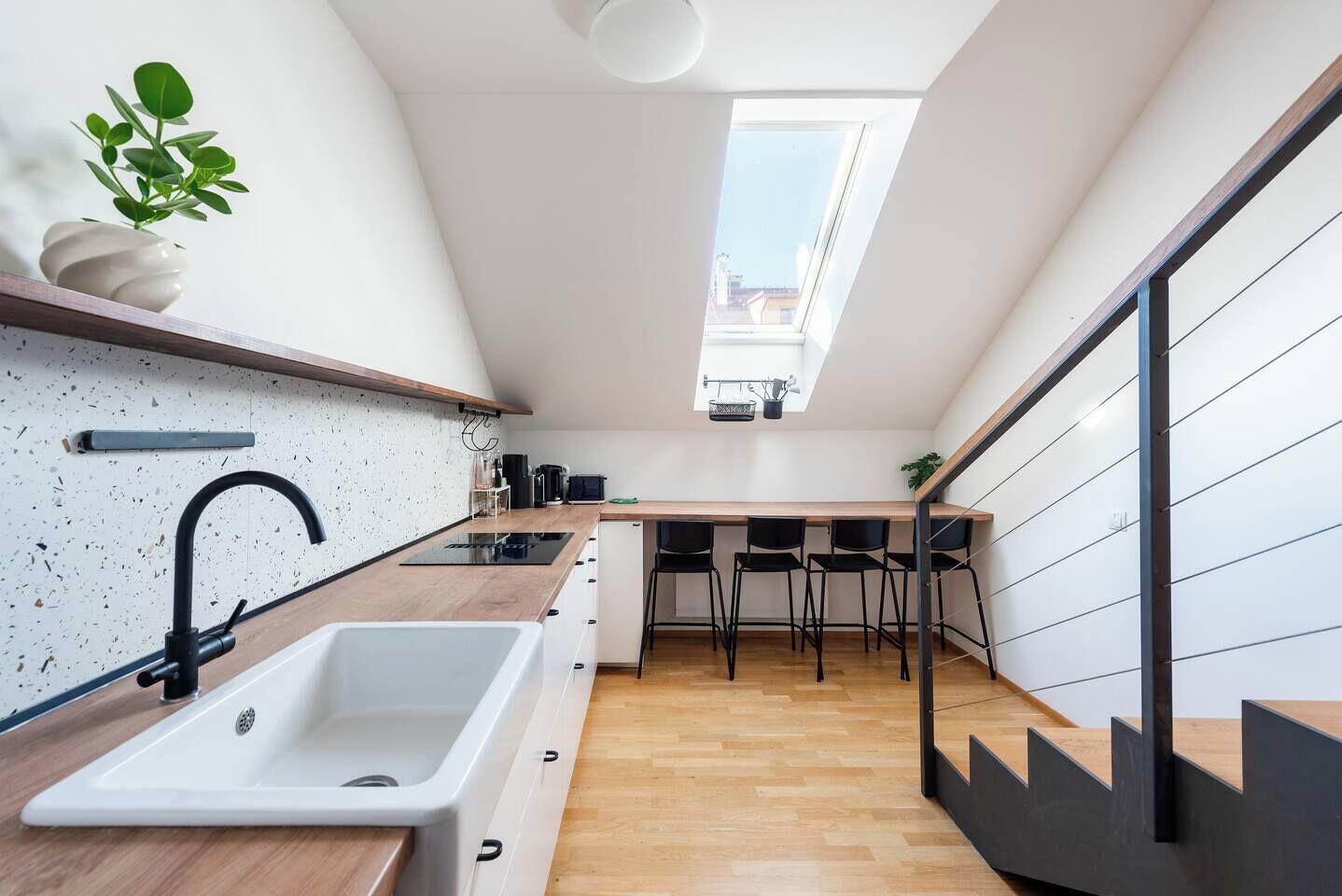 Una cocina moderna con tragaluz, encimera de madera y sillas negras.
