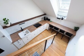 A modern kitchen with a wooden countertop, white cabinets, and a black sink. - Bright Duplex Loft near Wenceslas Square (Prague 2)