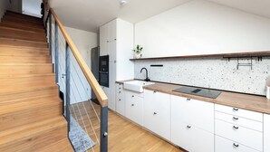 A modern kitchen with white cabinets, a wooden countertop, and a stainless steel sink. - Bright Duplex Loft near Wenceslas Square (Prague 2)