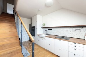 A modern kitchen with white cabinets, a wooden countertop, and a stainless steel sink. - Bright Duplex Loft near Wenceslas Square (Prague 2)