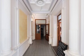 A hallway with white columns, a black and white patterned floor, and a signboard with menu items. - Bright Duplex Loft near Wenceslas Square (Prague 2)