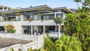 A modern multi-story residential building with balconies, outdoor seating, and lush greenery. - Penthouse 1 | Stylish Beachside Retreat (Sapphire Beach)