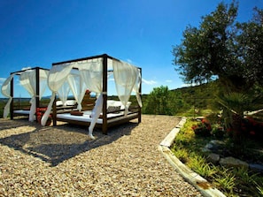 A two-tiered outdoor bed with white canopies, set on a gravel surface with a view of a green landscape and a clear sky. - Luxuriöses Landhaus für 16 Personen mit Pool und by Interhome (Sant Llorenç des Cardassar)