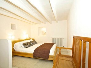 A bedroom with a wooden bed, white walls, a radiator, and a window. - Luxuriöses Landhaus für 16 Personen mit Pool und by Interhome (Sant Llorenç des Cardassar)