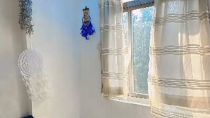 Una habitación con cama, ventana con cortinas y adornos en la pared.