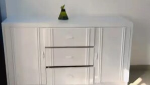 Un mueble blanco con tres cajones y un adorno pequeño en la parte superior.