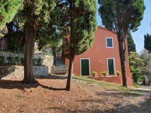 A building with a red facade, a green door, and a small window. There are trees in front of the building. - Collina Lagomare by Interhome (Corsanico)