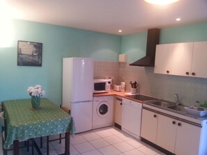 A compact kitchen with a washing machine, microwave, and sink. - 2 Personen by Interhome (Labruguière)