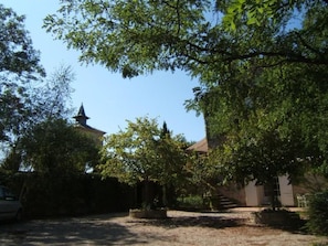 A courtyard with trees, a building with a tower, and a gravel path. - 2 Personen by Interhome (Labruguière)