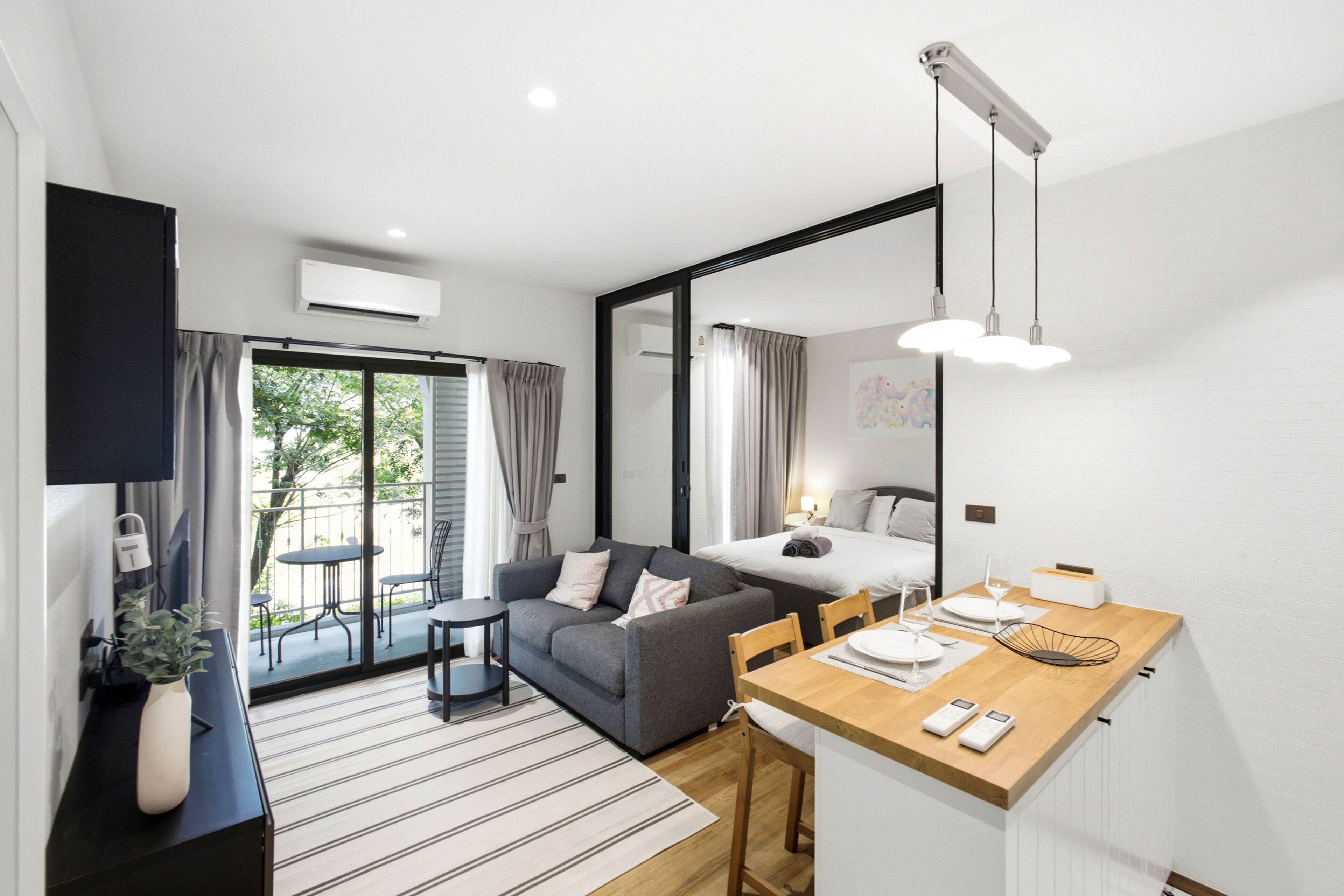 Quarto de hotel moderno com sofá, mesa de jantar, cama e varanda com cortinas.