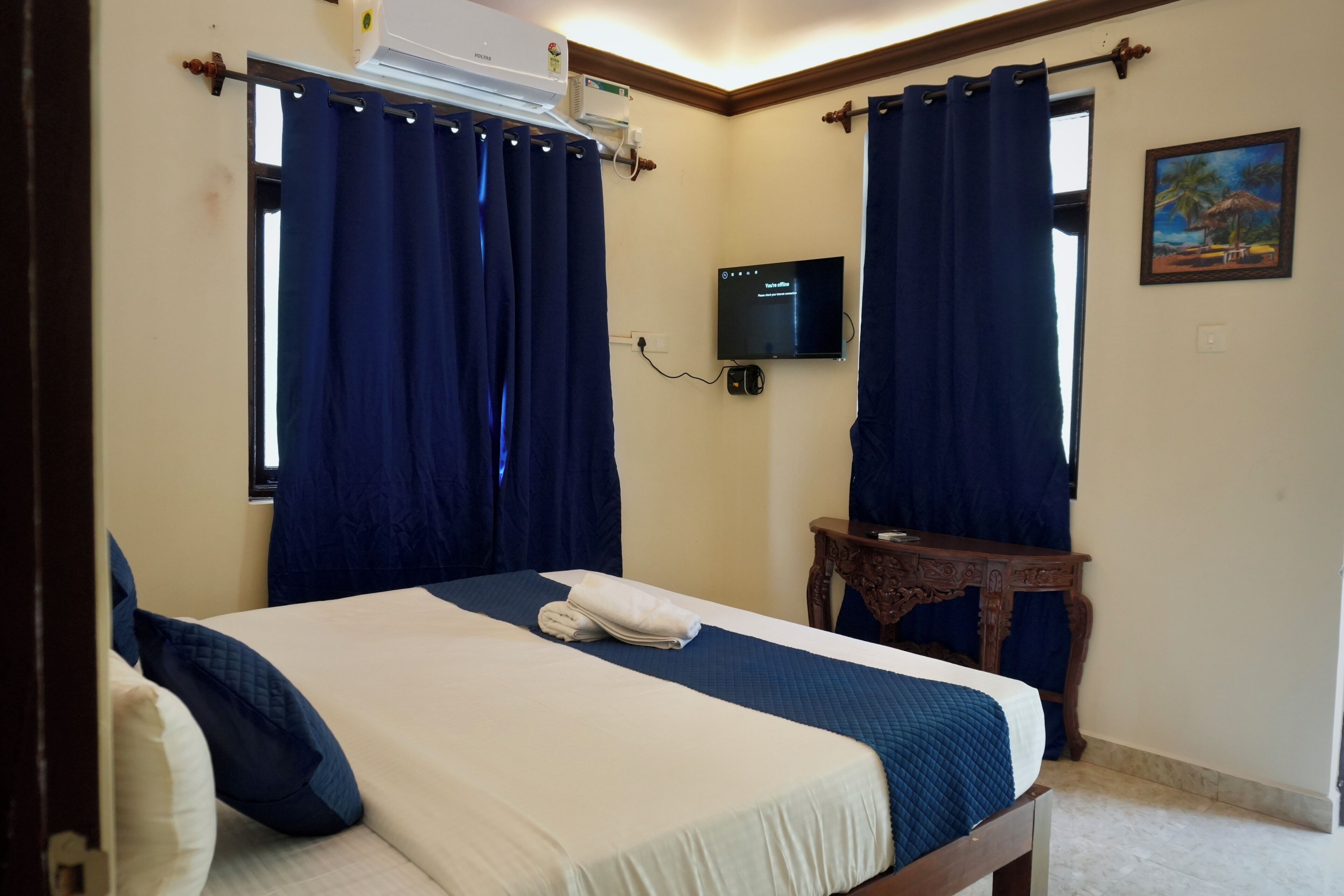 A hotel room with a bed, curtains, a television, and a small table.