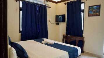 A hotel room with a bed, curtains, a television, and a small table.