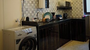 A compact kitchen with a washing machine, a microwave, and a sink.
