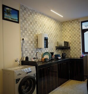 Una cocina compacta con lavadora, microondas y fregadero.