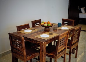 Una mesa de madera con cuatro sillas, un frutero y una taza azul sobre individuales.