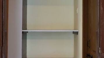 Een kast met drie planken en twee houten kledinghangers.
