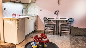Una cuina compacta amb un rentapeus, armaris i zona de menjador amb dues cadires i una taula.