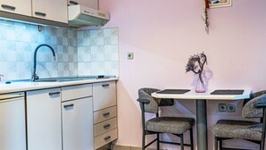 Una cuina compacta amb rentaplats integrat, un rentavaixelles, un taulell i zona menjador amb dues cadires i taula petita.