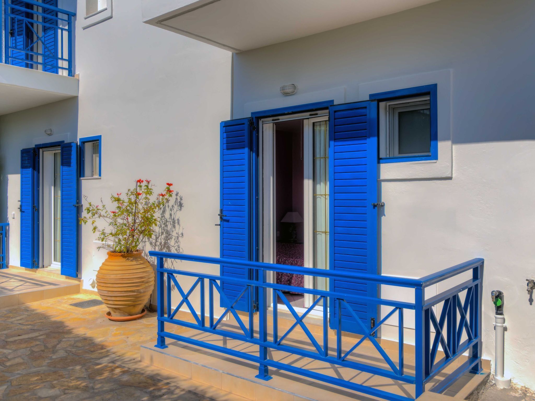 Ein Gebäude mit blauen Fensterläden, einem Blumentopf und einer gefliesten Eingangshalle.