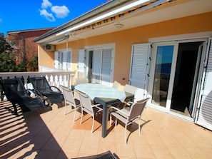 A patio with a table and chairs, a grill, and a sliding glass door. - Wohnung in Novi Vinodolski mit Grill, Garten und by Interhome (Novi Vinodolski)