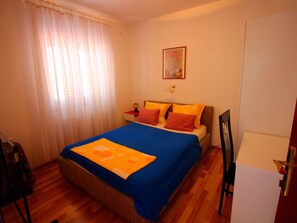 A bedroom with a bed, a nightstand, a lamp, a chair, and a painting on the wall. - Wohnung in Novi Vinodolski mit Grill, Garten und by Interhome (Novi Vinodolski)