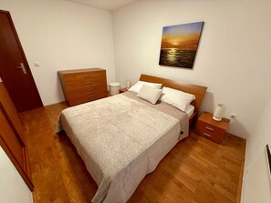 A bedroom with a bed, wooden dresser, bedside tables, and a painting on the wall. - Apartment Val by Interhome (Crikvenica)