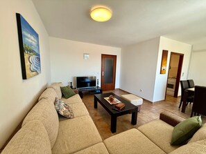 A living room with a sofa, coffee table, TV, and a painting on the wall. - Apartment Val by Interhome (Crikvenica)