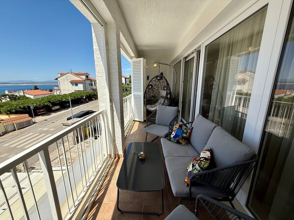 Un balcone con un divano, una sedia amaca e un tavolo.