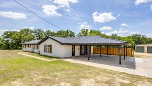 Een laag gebouw met een overdekte patio, een garage en een verzorgd gazon.