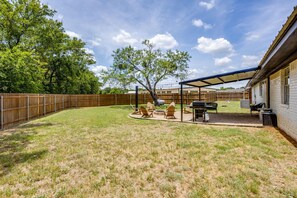 A backyard with a covered patio area, a barbecue grill, and outdoor seating.