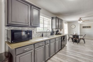 A modern kitchen with grey cabinets, a built-in microwave, and a dining area with a round table and chairs.