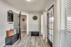 A hallway with a wooden floor, a bench with a cushion, a clock, and a star decoration on the wall.