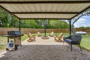 Un patio techado al aire libre con una parrilla, una zona de estar y un hogar para fuego.