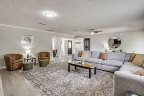 A living room with a sofa, armchairs, a coffee table, and a rug.