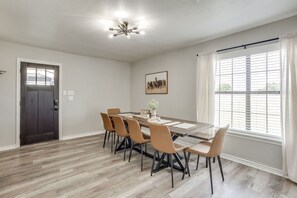 A dining area with a table, chairs, and a ceiling light fixture.