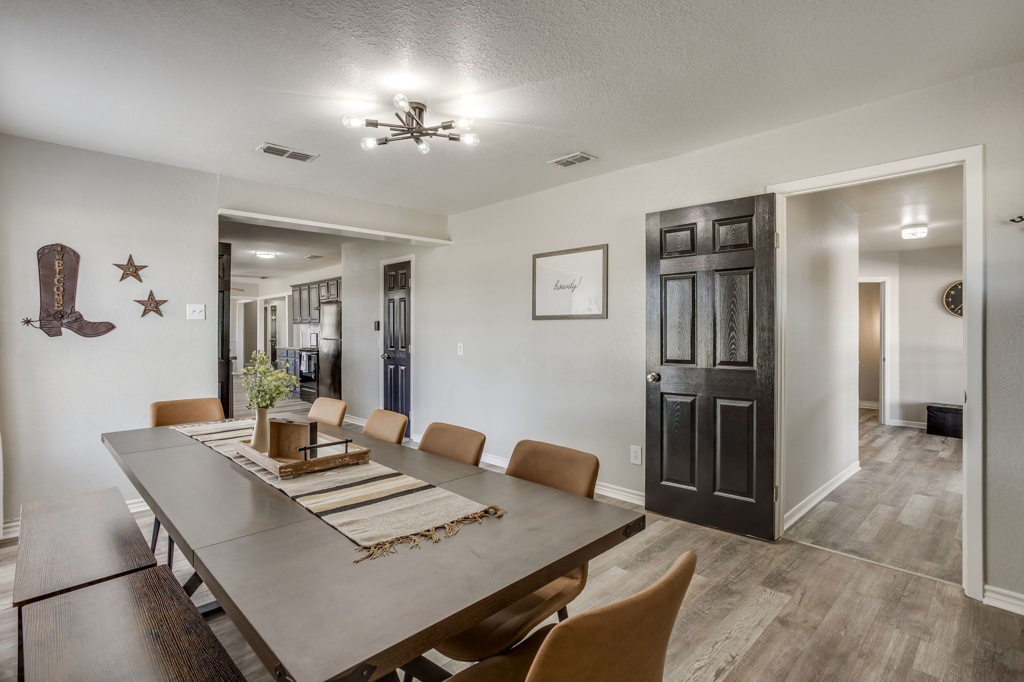 A dining area with a long table, chairs, and a ceiling light fixture.