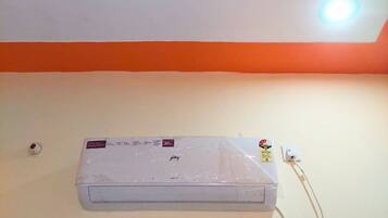 Ein Zimmer mit weißer Decke, einer grünen, dreieckigen Dekoration und einer weißen Klimaanlage an der Wand.