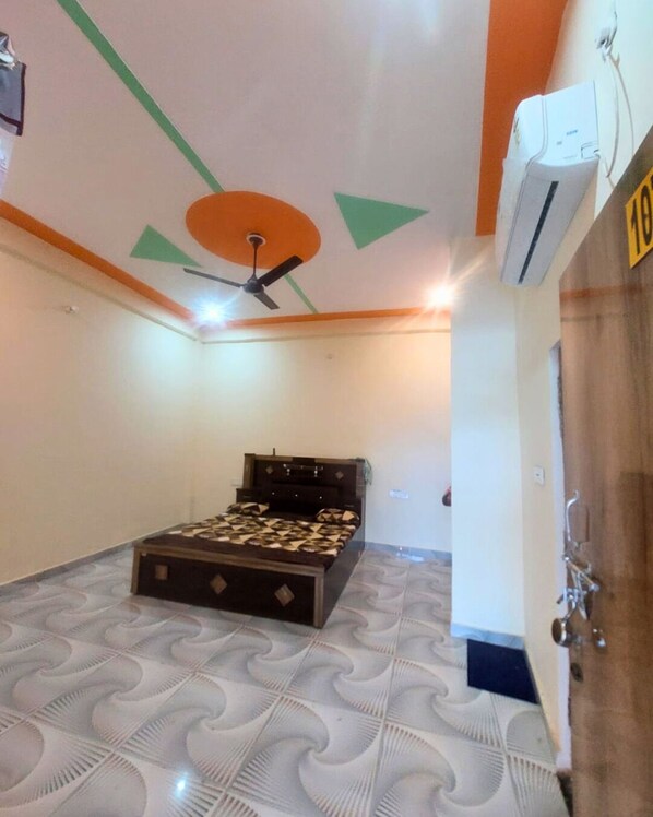 Un dormitorio con una cama, un ventilador de techo y un aire acondicionado.