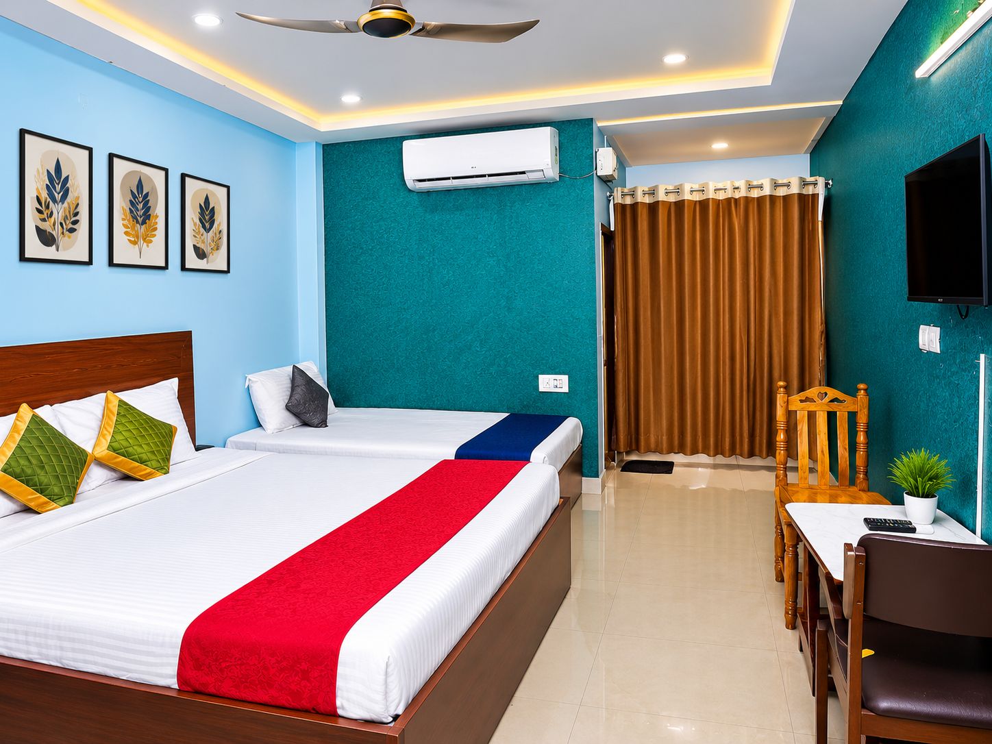 Una habitación de hotel con cama, escritorio, silla, televisor y aire acondicionado.